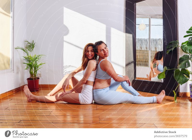 Entzückte Frauen beim Yoga zu Hause üben Zusammensein beweglich Asana ruhen Lächeln Freund Sportbekleidung Stock heimwärts Gesundheit Wellness sitzen Glück