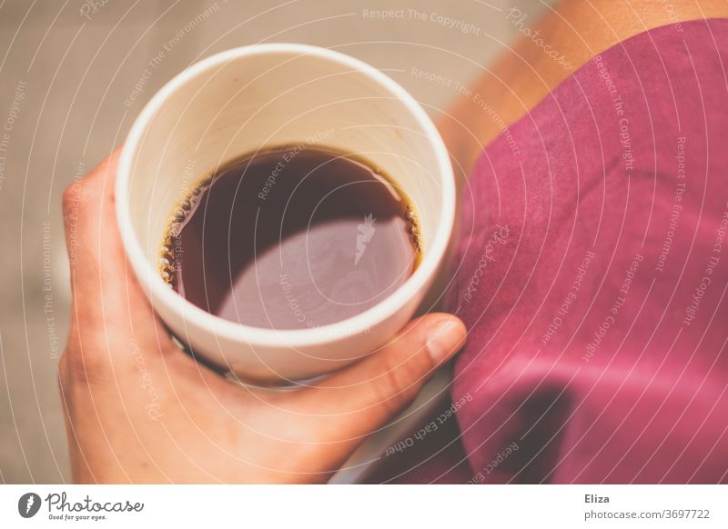 Eine Frau hält einen Becher mit Kaffee in der Hand Koffein draußen Hell Tasse Morgen Pause Filterkaffee schwarzer Kaffee