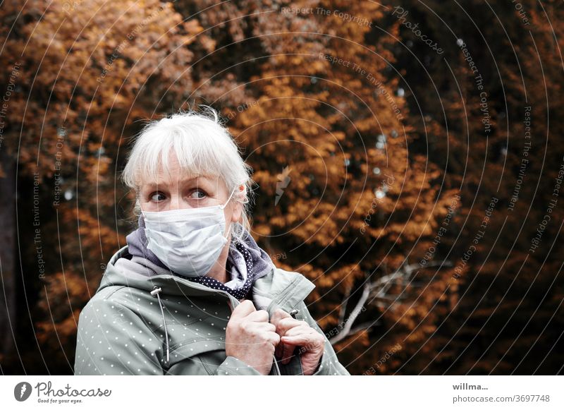 Blonde Frau mit medizinischer Maske schaut skeptisch - Angst vor Ansteckung Mundschutz Ansteckungsgefahr Corona Herbst ängstlich besorgt fragend vorsichtig