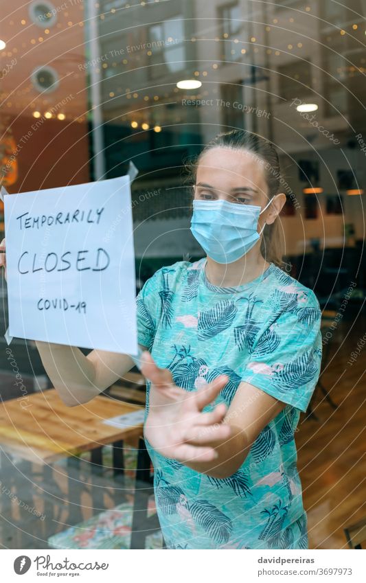 Frau platziert Coronavirus-Verschlusszeichen Besitzer Gesichtsschutzmaske Klebeplakat Abschluss covid-19 Café Operationsmaske Quarantäne vorübergehend Virus Bar