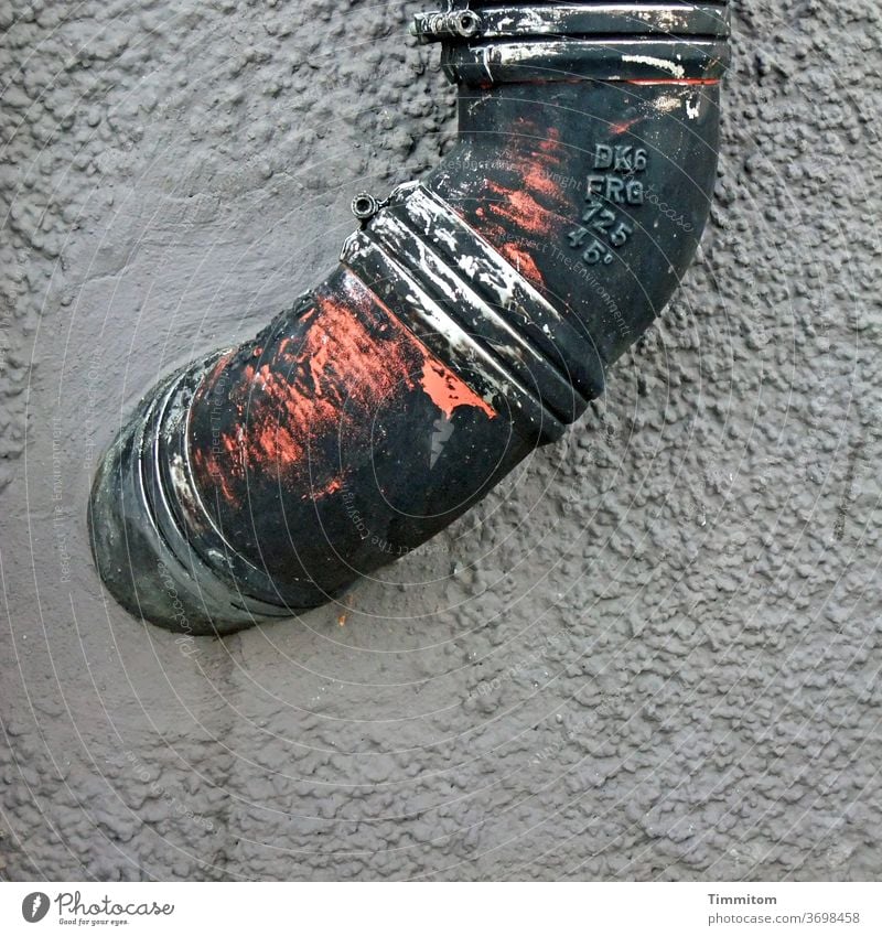 Ein metallenes Knie präsentiert sich Regenfallrohr Fallrohr Wand Fassade Gebäude Regenrohr Ecke Menschenleer Farbfoto Metall Beschriftung Putzfassade Farbe