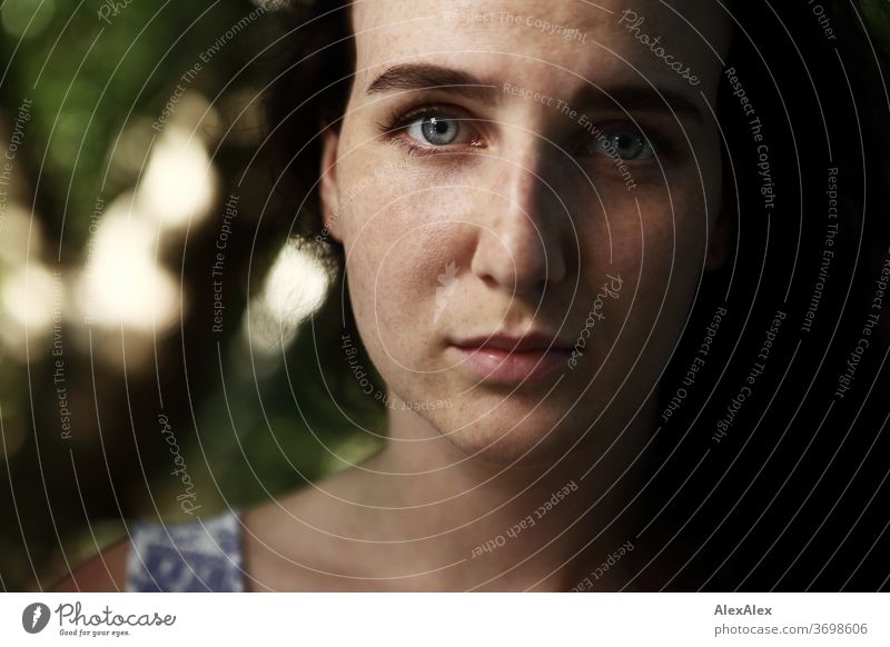 Nahes Portrait einer sommersprossigen Frau in einem Wald im Sommer zart Schatten Licht sportlich feminin Empathie Gefühle emotional Blick in die Kamera Porträt