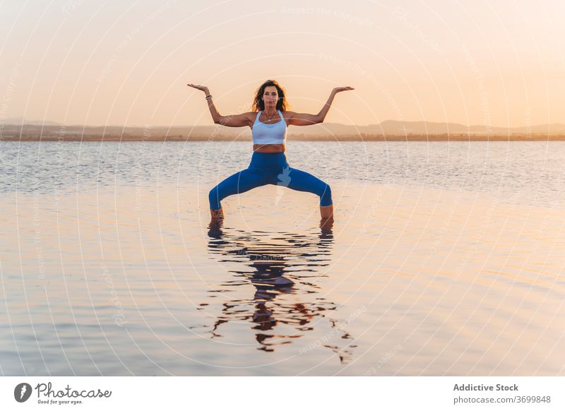 Junge Frau in Göttin Asana reflektiert in See Wasser Yoga üben Pose Ukata Konasana stehen Harmonie Sprit Geist Anmut Fokus Reflexion & Spiegelung Gleichgewicht