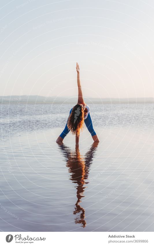 Frau führt Yoga-Asana im See Wasser üben Pose stehen prasarita padottanasana Vorwärtsbeuge gedreht verdrehen Reflexion & Spiegelung Fokus Harmonie Gleichgewicht