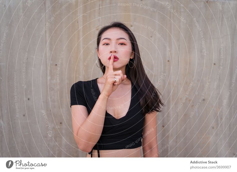 Ethnische Frau zeigt Schweigegebärde stumm gestikulieren Zeichen Ruhe Zeigefinger Windstille zeigen shh geheim ethnisch asiatisch ruhig charmant manifestieren
