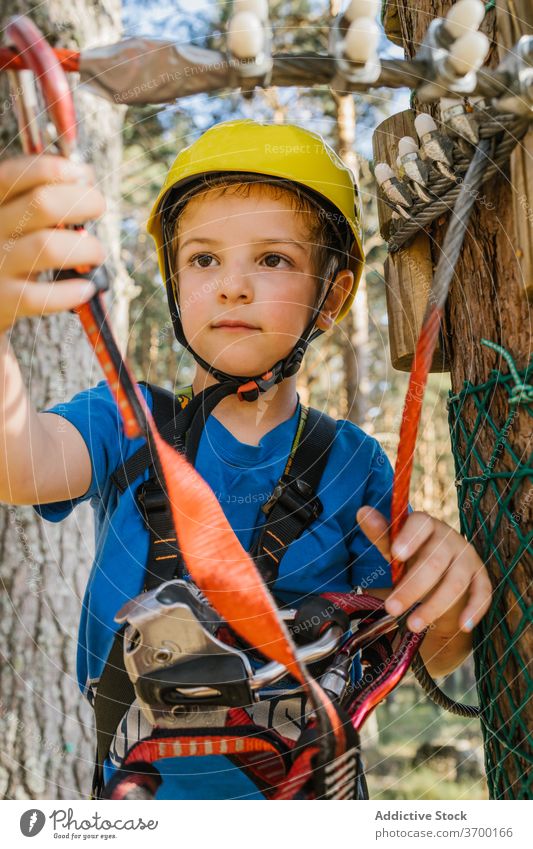 Süßer Junge im Abenteuerpark Park Gerät Karabiner Sicherheit Kabelbaum unterhalten Spaß haben Wochenende Sommer Seil behüten Schutzhelm extrem sicher Aktivität