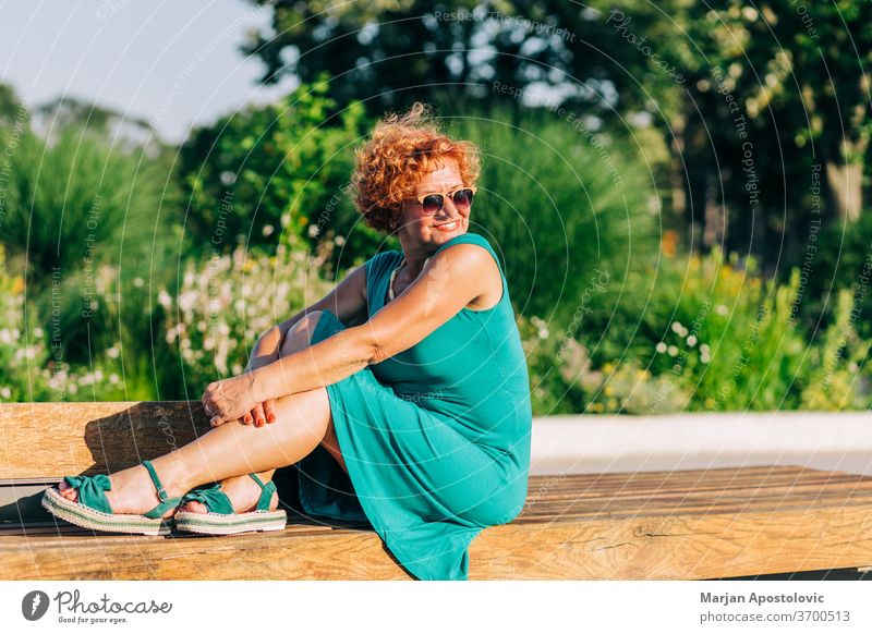 Reife Frau sitzt im Sommer auf der Parkbank 60s Erwachsener Lebensalter gealtert allein schön Schönheit Bank lässig Kaukasier heiter Großstadt Selbstvertrauen