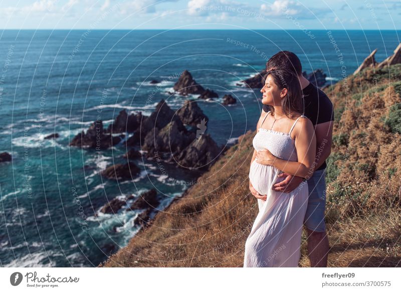 Schwangeres Paar auf einer Klippe in der Nähe des Ozeans schwanger Klippen Beteiligung Bauch erwartend Schwangerschaft Textfreiraum Baby Mutter Trächtigkeit