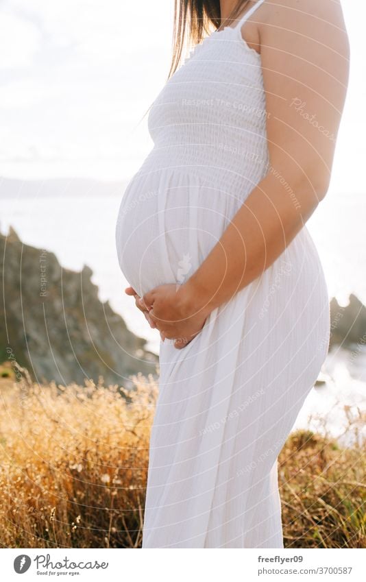 Detail eines schwangeren Körpers von der Seite Schwangerschaft Textfreiraum Beteiligung Hände Pflege erwartend Bauch Baby Nachbau Mutter weißes Kleid