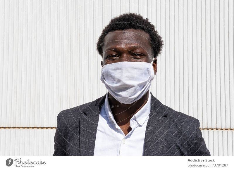 Fröhlicher schwarzer Geschäftsmann mit Schutzmaske Mundschutz behüten Coronavirus Pandemie COVID heiter Unternehmer formal Porträt Mann positiv Straße jung