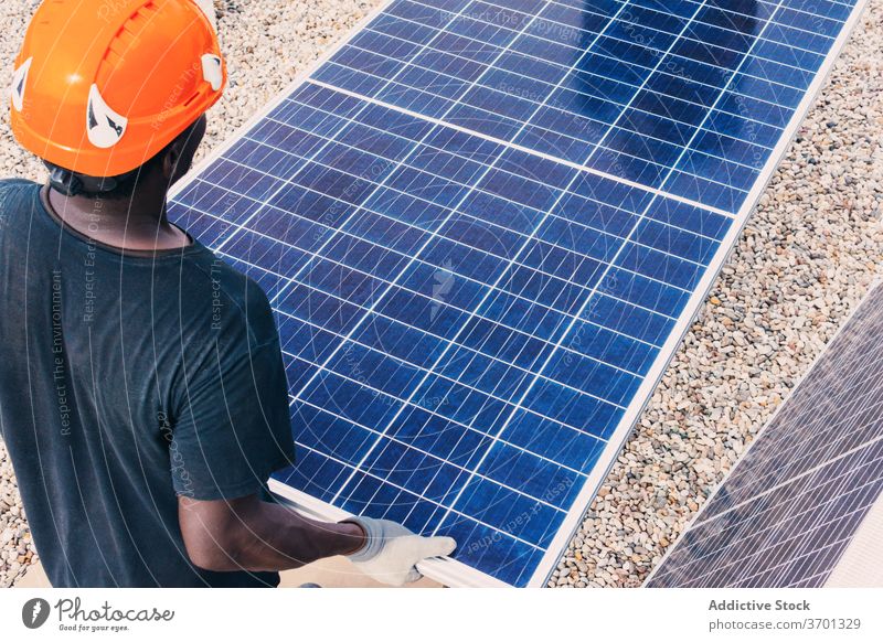 Ethnischer Mann mit Solarpanel auf einer Baustelle solar Panel industriell alternativ Arbeit Konstruktion Standort nachhaltig Erneuerung ethnisch schwarz