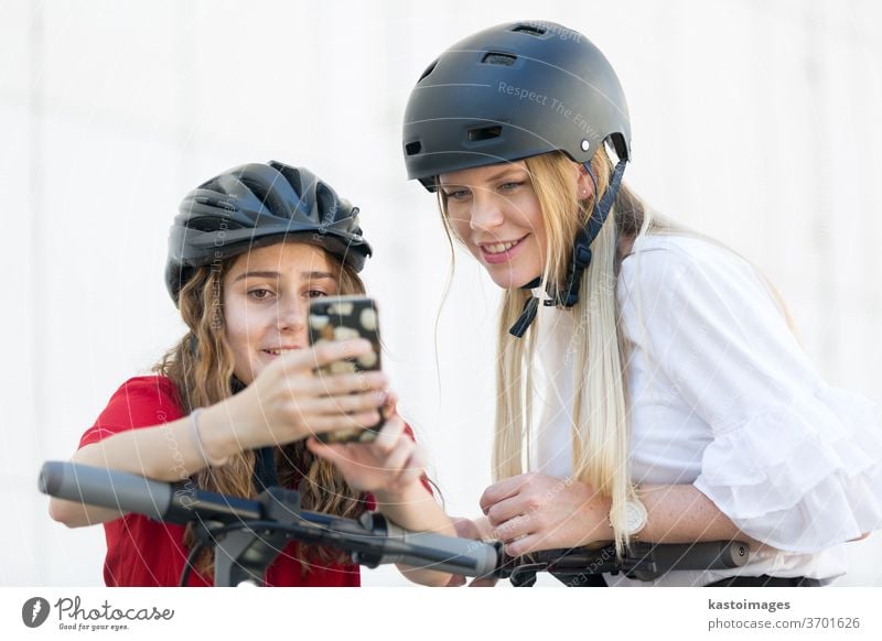 Teenager-Mädchen, die eine mobile Anwendung zum Freischalten und Ausleihen von öffentlichen Leihelektrorollern in der städtischen Umgebung nutzen. Umweltfreundlicher moderner öffentlicher Stadtverkehr in Ljubljana, Slowenien.
