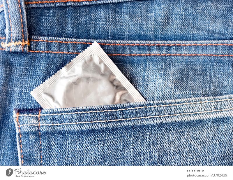 Ein Kondom springt aus der Vordertasche einer Jeans Jeanshose Textur Baumwolle Gewebe Schutz Rudel Tasche Sicherheit blau sicher Gesundheit Verhütungsmittel