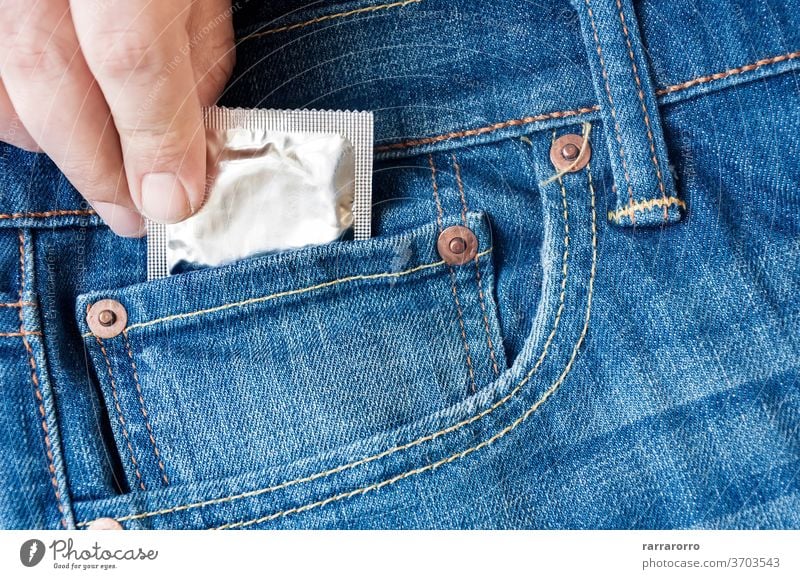 die Hand eines Mannes, der ein Kondom in der Tasche seiner Jeans nimmt Jeanshose Person Sicherheit Lifestyle jung Konzept Gesundheit Sex Erwachsener