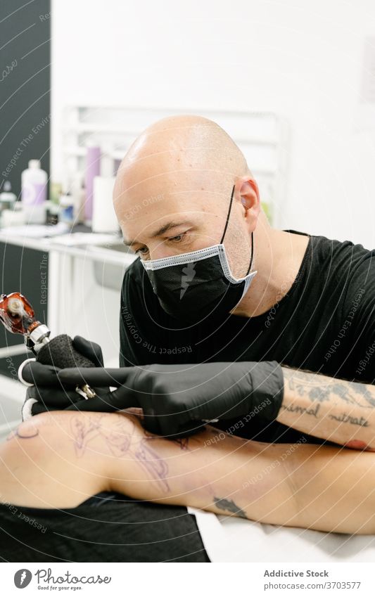 Männlicher Meister macht Tattoo im Salon Tätowierer Maschine Klient professionell Kunst Körper Tisch Lügen Gerät Künstler Arbeit Stil kreativ Tusche Atelier