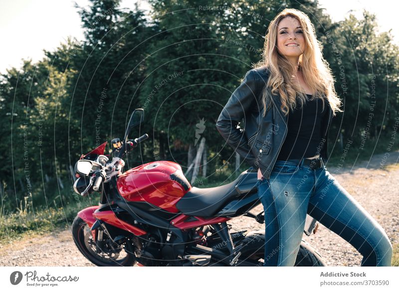Fröhlich Biker in der Nähe Motorrad in der Landschaft Motorradfahrer modern Sport Frau Verkehr heiter Lederjacke trendy Lächeln Glück stehen Fahrzeug