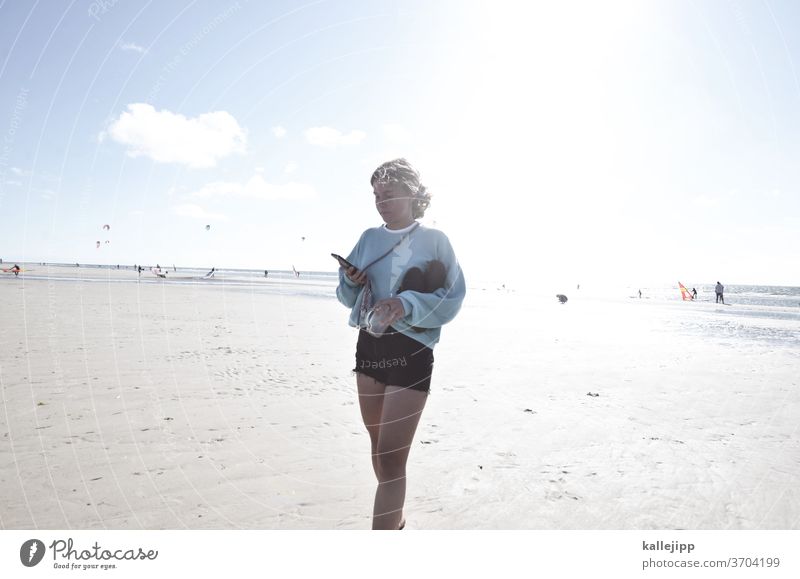 Mädchen am Strand mit Handy Teenagermädchen Teenagerin teenager Mobilität Sommer Shorts Außenaufnahme Frau Farbfoto Jugendliche Natur Junge Frau schön jung