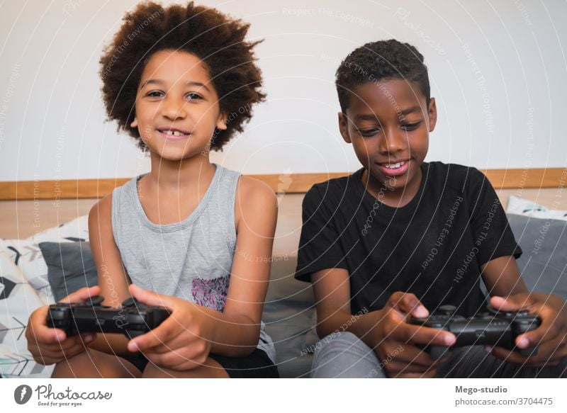 Zwei Brüder spielen zu Hause Videospiele. Zusammensein Spiel Regler Afroamerikaner Aussehen im Innenbereich Kinder Entertainment Aktivität heiter Spaß Porträt