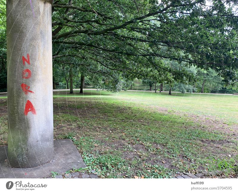 Nora Schriftzug auf Säule im Park rot Frühling rote schrift Garten Natur Pflanze Buchstaben grün