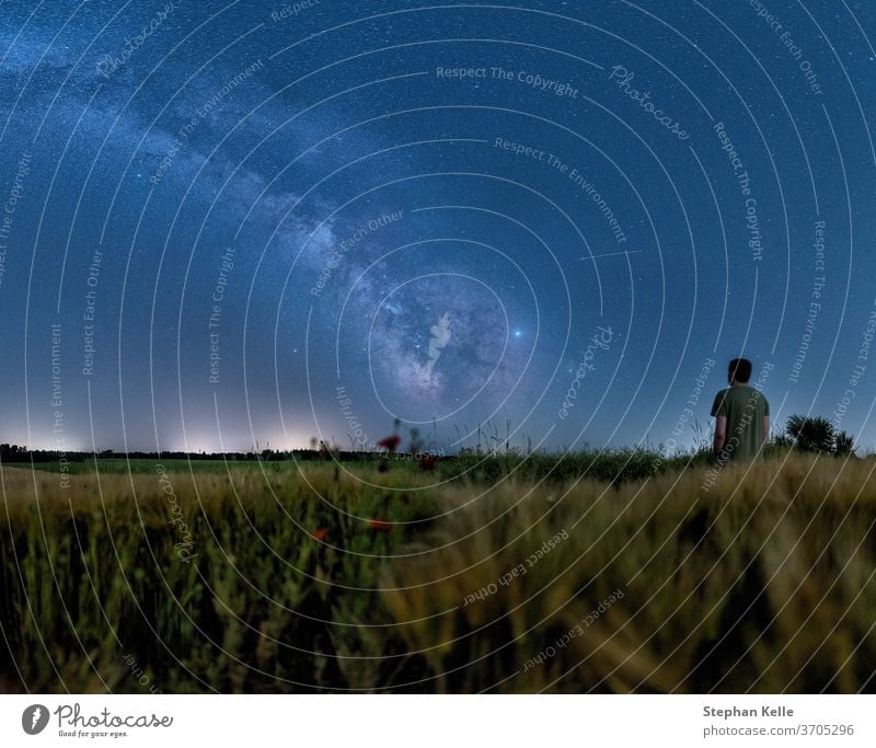 Mann beobachtet die Milchstraße, wenn er nachts an einem wachsenden Feld steht zuschauen Raum galaktisches Zentrum Sternenlicht Astrofotografie Hintergrund