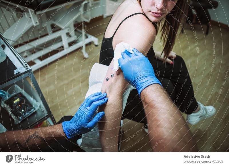 Tätowierer wischt den tätowierten Arm eines Kunden ab Tattoo Wischen Klient Leckerbissen Hygiene beenden Arme Verfahren Serviette Salon professionell Arbeit