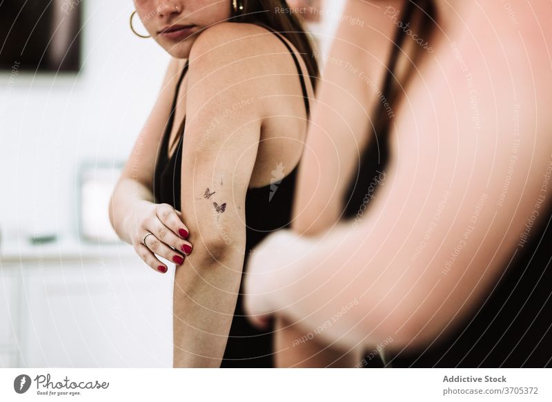 Glückliche Frau mit neuem Tattoo schaut in den Spiegel Arme untersuchen zufrieden Salon Klient jung Kunst Kultur Reflexion & Spiegelung Stil Kunde Mode Dienst