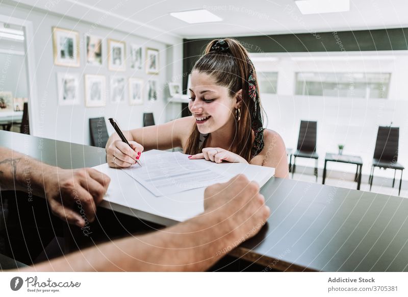 Frau füllt Papierdokument aus Tattoo Salon Zeichen Schriftstück Abfertigungsschalter Rezeption Verfahren Klient jung Kunde modern Stil Dienst vorbereiten