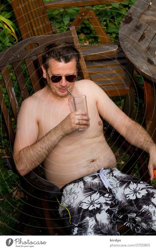 Mann mit Sonnenbrille und freiem Oberkörper genießt ein Getränk im Freien Sommer Wärme freier Oberkörper trinken genießen Pilotenbrille Trinkhalm sitzend Garten