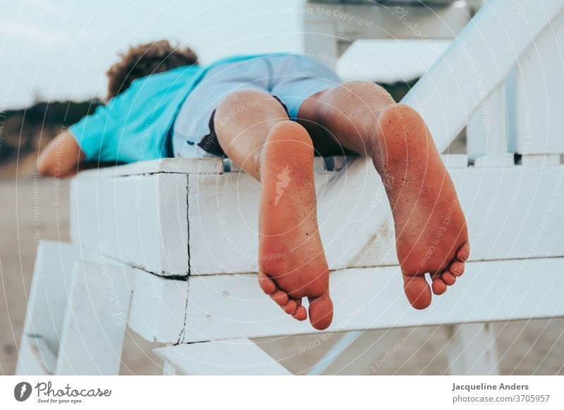 Junge liegt barfuß auf einem Stuhl am Strand Füße Kind Beine Fuß Sommer Barfuß Sand Außenaufnahme Zehen Ferien & Urlaub & Reisen Meer Erholung Mensch Sonne