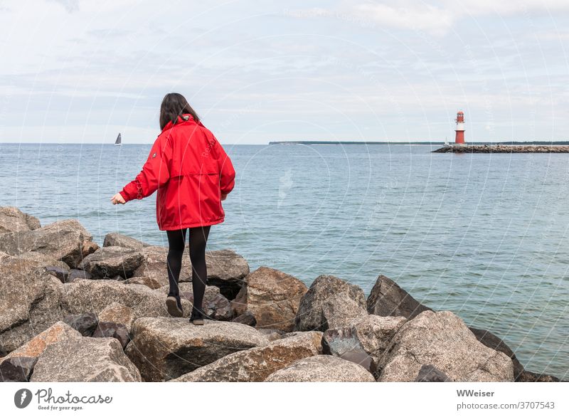 Junges Mädchen balanciert auf den großen Steinen der Westmole junge Frau Gleichgewicht balancieren Felsbrocken Mole Wetsmole Warnemünde Rostock Leuchtturm