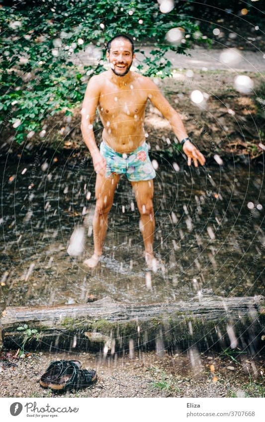 Ein Mann badet im Sommer in einem Bach und spritzt mit Wasser. Erfrischende Abkühlung bei dieser Hitze. Baden spritzen planschen Erfrischung Freude nass
