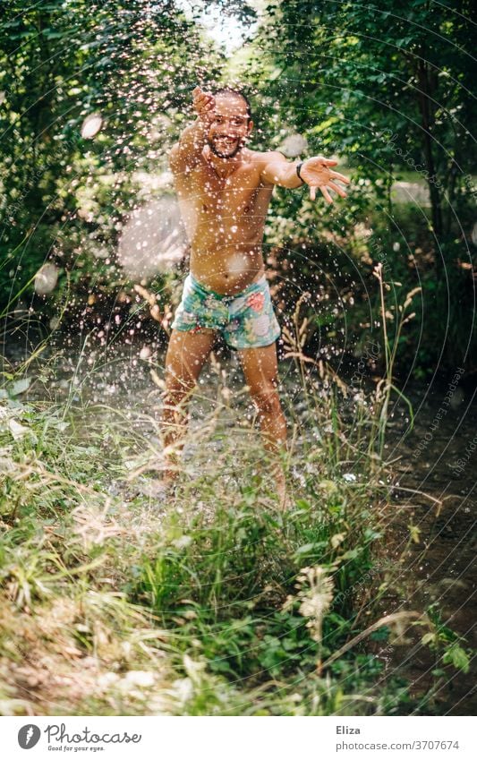 Ein Mann badet im Sommer in einem Bach und spritzt mit Wasser. Erfrischende Abkühlung bei dieser Hitze. Baden spritzen planschen Erfrischung Freude nass