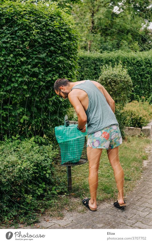 Ein Mann in Sommerkleidung sucht etwas in einem Mülleimer am Wegesrand suchen Mensch neugierig wegwerfen verloren containern