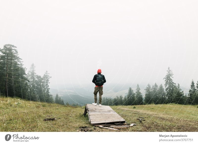 Naturforscher genießt den Blick auf eine neblige Bergkette Abenteuer allein Rucksack Backpacker Umwelt erkunden Entdecker erkundend Nebel Wald Freiheit grün