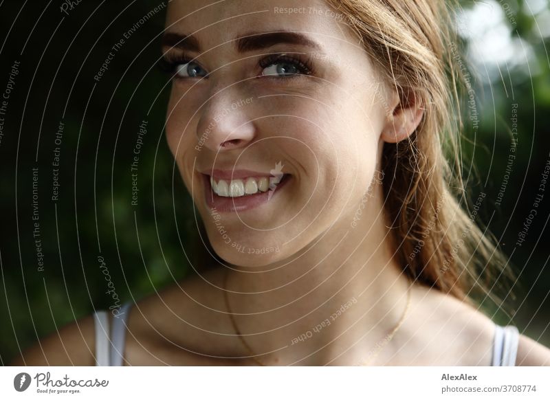Nahes Portrait einer jungen Frau mit Wangengrübchen in der Natur Licht sportlich feminin Gefühle emotional Blick in die Kamera Porträt Zentralperspektive