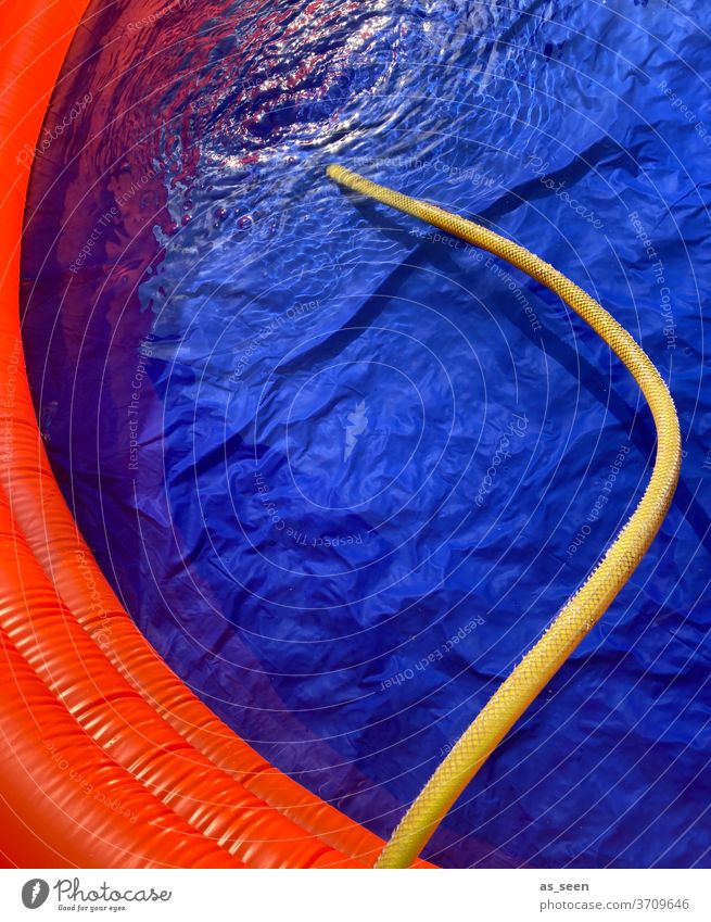 Mit dem Gartenschlauch den Pool mit Wasser befüllen Planschbecken gelb blau orange Frabe nass Design Reflexion & Spiegelung Sommer Farbfoto Schwimmbad