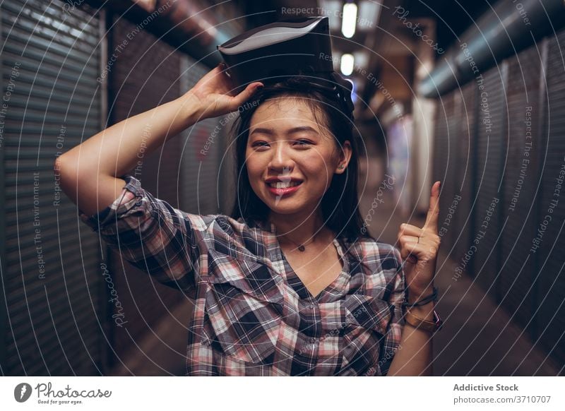 Asiatische Frau mit VR-Brille auf der Straße virtuell Realität Schutzbrille Virtuelle Realität nach oben zeigen gestikulieren Erfahrung asiatisch ethnisch Index