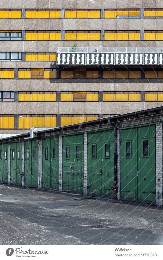 Eine Reihe von Garagen vor einem Verwaltungsgebäude mit originellem Balkon Holztore Türen Fassade Fenster geschlossen Muster Berlin Westhafen gelb Design