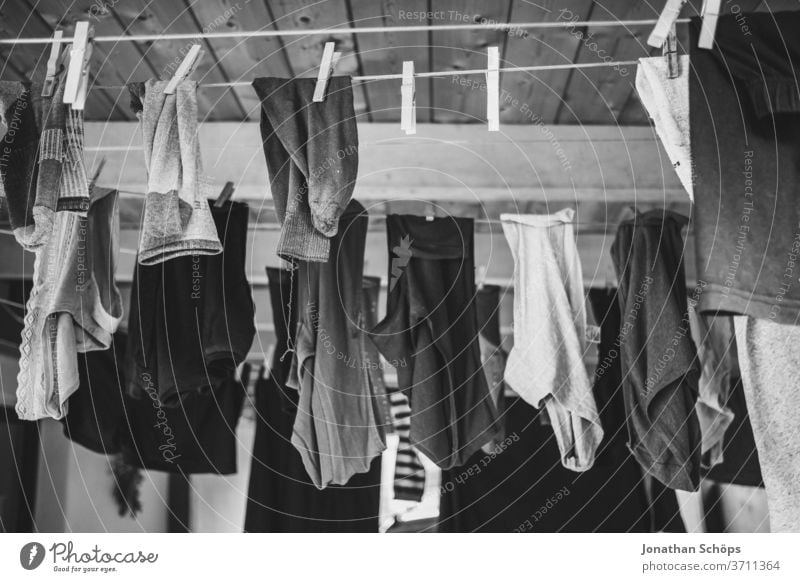 Wäsche auf der Leine in einem Carport Haus Klammern Klamotten Kleidung Socken Trocknen Wäscheleine draußen hängen schwarzweiß waschen trocknen Wäsche waschen