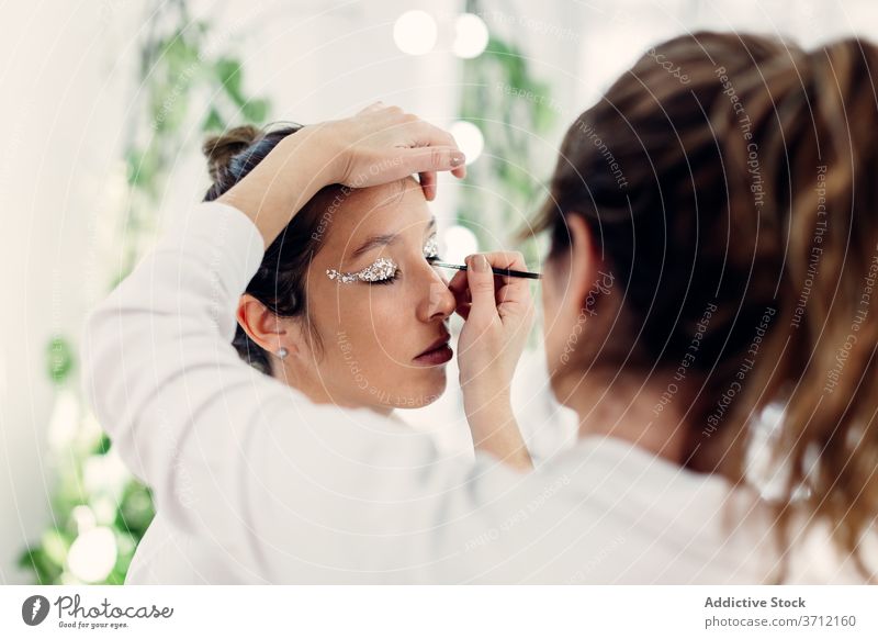 Visagistin beim Schminken im Salon Make-up professionell Künstler Kajal Glitter bewerben visagiste Frauen Zusammensein Model Atelier Schönheit Kosmetik elegant