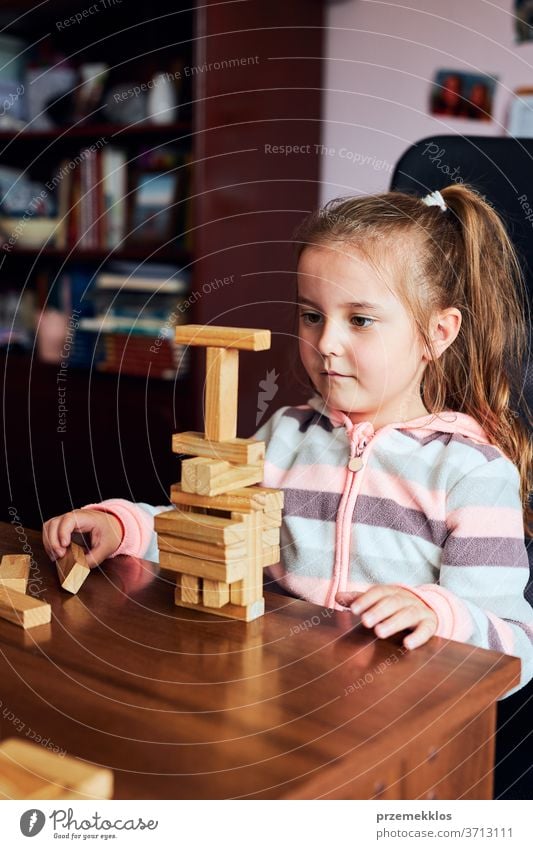 Kleines Mädchen im Vorschulalter, das mit Holzklötzchen spielt, die einen Turm bauen. Konzept für den Bau eines Hauses Kind Spielen Blöcke Spielzeug biulding