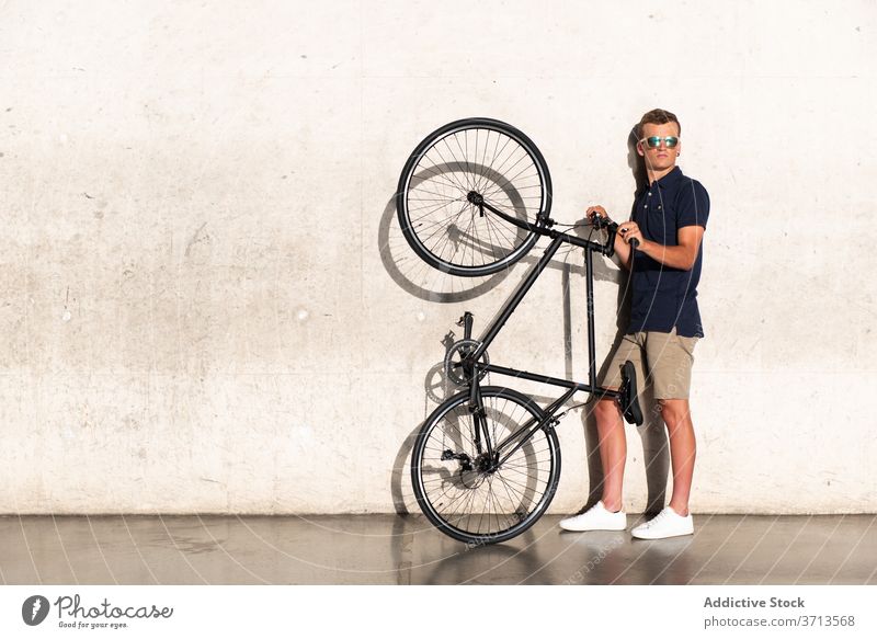 Mann trägt sein Fahrrad auf Betonwand Erwachsener blond lässig Kaukasier Fahrradfahren Radfahrer Lifestyle fettarm männlich Halt tausendjährig Mobilität modern