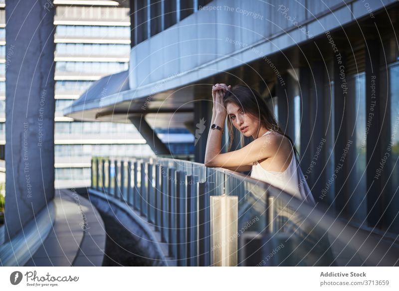 Nachdenkliche junge Frau steht in der Nähe von modernen Gebäude nachdenklich besinnlich einsam Denken urban traurig Zeitgenosse nachdenken Lifestyle träumen