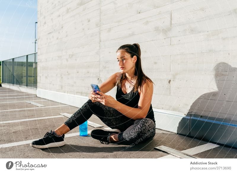 Starke Sportlerin, die ein Smartphone benutzt Frau stark benutzend nachdenklich Bizeps Text Athlet besinnlich Sportbekleidung Straße Training Gesundheit Gerät