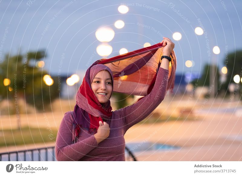 Lächelnde arabische Frau im Hidschab auf der Straße Hijab angezogen muslimisch religiös Großstadt Abend Kopfschmuck Inhalt ethnisch Glück Stil froh Freude