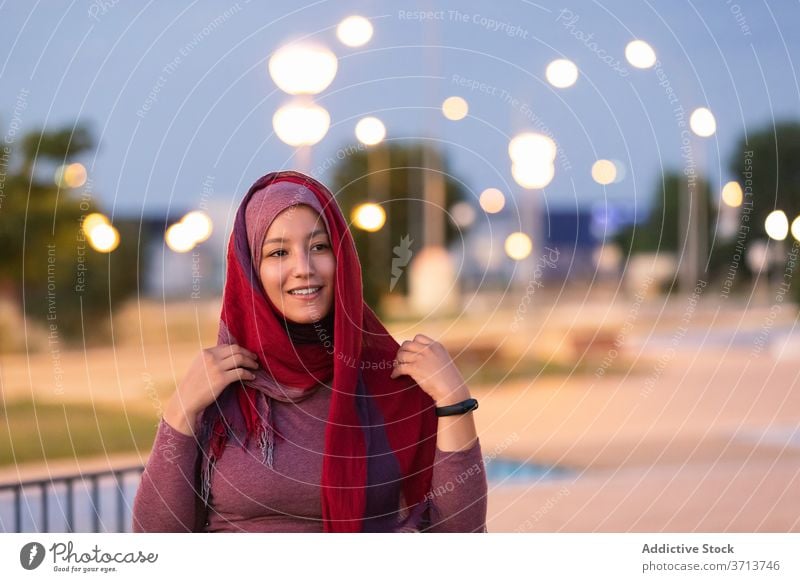Lächelnde arabische Frau im Hidschab auf der Straße Hijab angezogen muslimisch religiös Großstadt Abend Kopfschmuck Inhalt ethnisch Glück Stil froh Freude