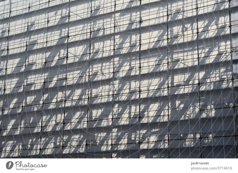 Vorfreude kommt auf, hinter dem Baugerüst Schattenspiel Strukturen & Formen Gerüstplane Sonnenlicht Symmetrie transparent Silhouette Streben Architektur