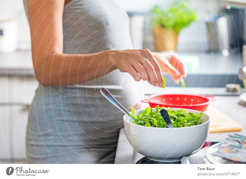 Schwangere junge Frau breitet sich einen leckeren Salat in der Küche zu wasche vegan Vegetarische Ernährung putzen essen Gesunde Ernährung Vegane Ernährung Hand