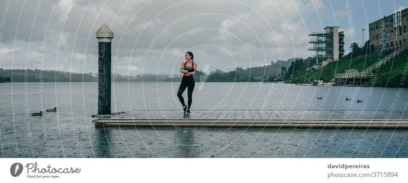 Sportlerin sieht den See vom Pier aus. Regen posierend verschränkte Arme Gelassenheit Boxerflechten Fitness passen Training regnet Mut Transparente Netz