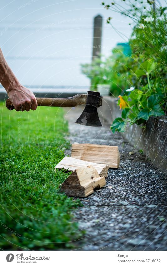 Mann hackt Holz mit einer Axt im Garten. Teilabschnitt. Brennholz hacken Gras grün draußen Außenaufnahme Natur Holzstapel Hand über40 Tag Brennstoff